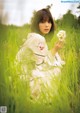 A woman in a white dress holding a flower in a field.